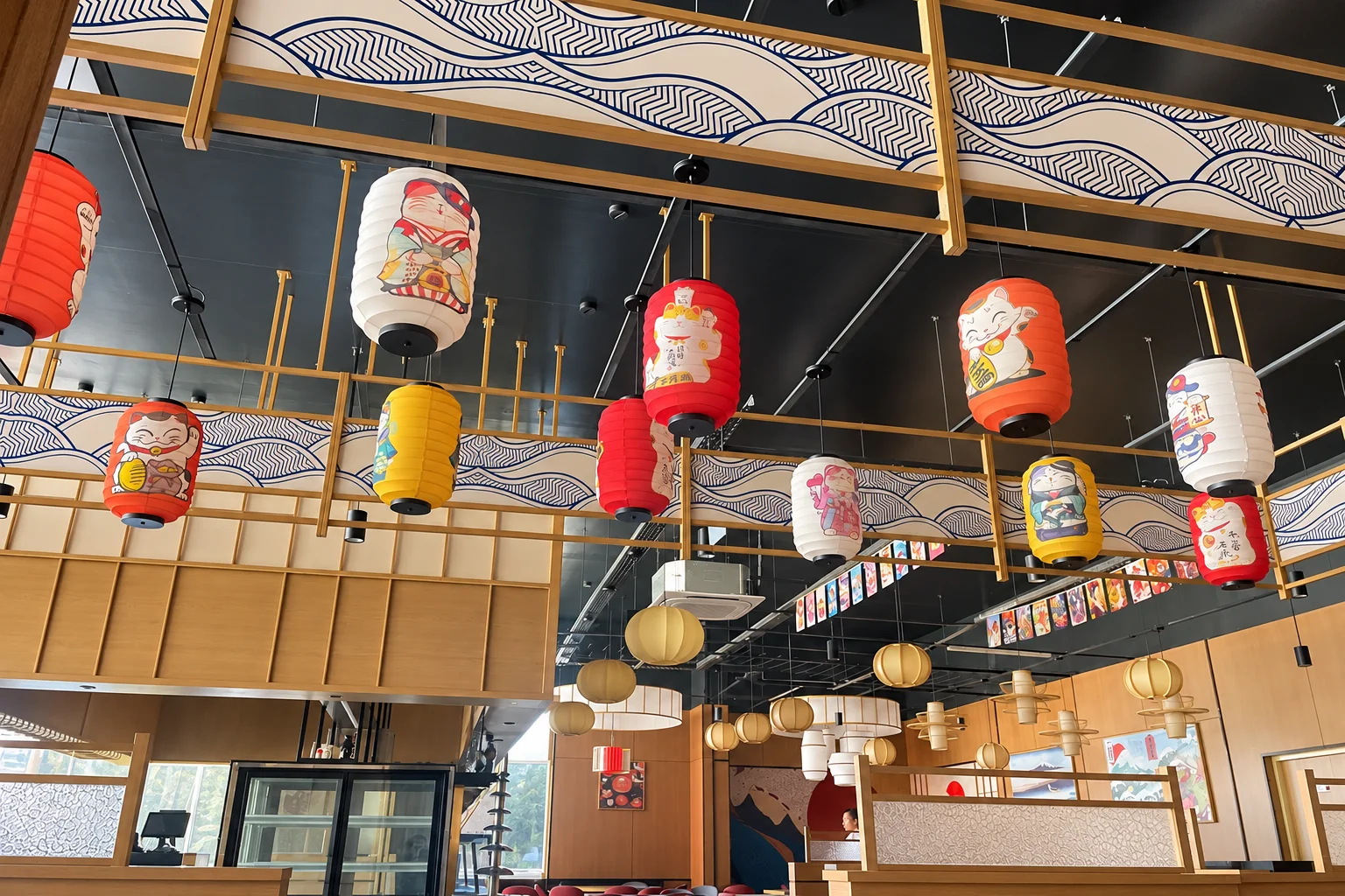 Dining room with colourful paper lanterns hanging under a wave-pattern ceiling.