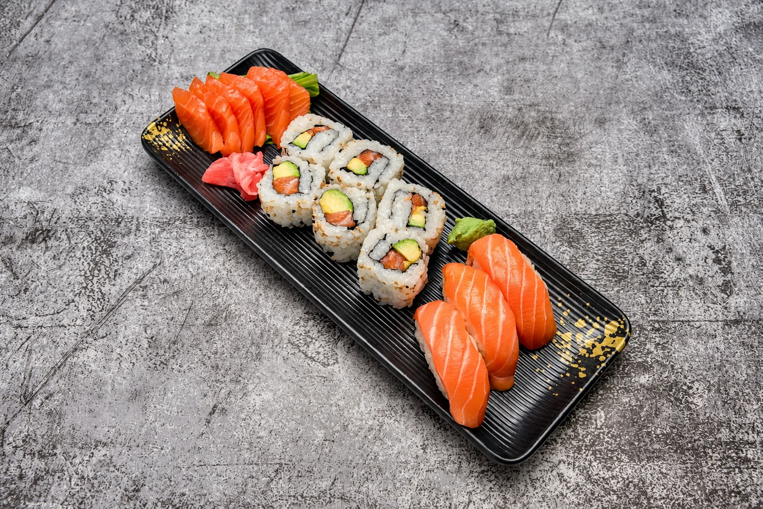 Salmon sashimi, california rolls and salmon nigiri on a black ribbed plate, grey concrete background.